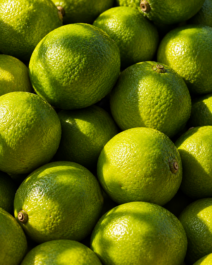 A pile of bright green limes, part of the green citrus note in Le Week End eau de parfum